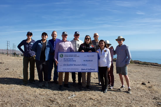 Asm. Hart, Sen. Limón and others on beach, holding up large ceremonial check
