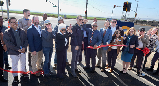 People holding long ribbon at ribbon cutting ceremony